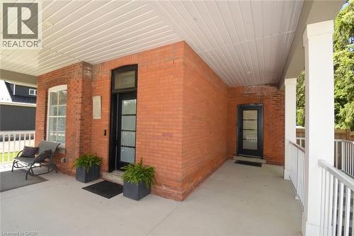 Expansive covered porch featuring a red brick facade and white railings. - 89 Lynden Road, Lynden, ON 