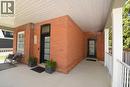 Expansive covered porch featuring a red brick facade and white railings. - 89 Lynden Road, Lynden, ON 