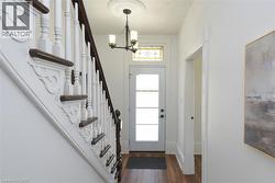 Foyer - detailed staircase with dark wood handrails and white balusters, and a front entry door featuring frosted glass panels and a stained glass transom - 