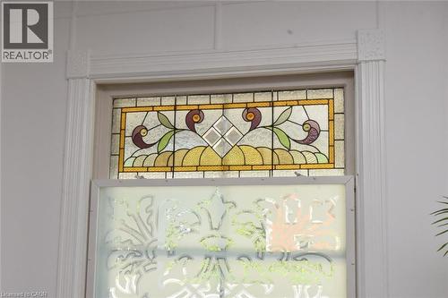 Window featuring an ornate stained glass transom and a frosted lower pane with a decorative pattern, framed by fluted trim and corner blocks - 89 Lynden Road, Lynden, ON 