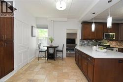 Kitchen featuring an expansive island with a light-toned countertop, rich wood-finish cabinetry, and a mosaic tile backsplash - 