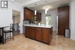 Kitchen featuring white quartz countertop, dark wood cabinetry, stainless steel appliances, and tile flooring - 