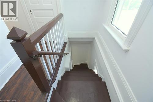 Staircase featuring dark wood-finish treads and risers, white balusters, and a rich brown newel post - 89 Lynden Road, Lynden, ON 