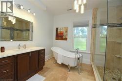 Bathroom featuring a freestanding clawfoot tub with a polished chrome faucet, a dark wood vanity with a white countertop, and a large framed mirror - 
