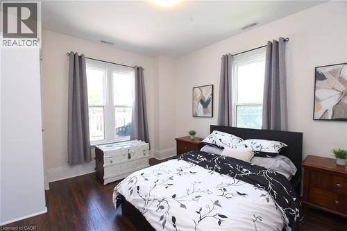 Bedroom featuring wood-finish flooring, two large windows, white baseboards, and a neutral wall color - 89 Lynden Road, Lynden, ON 