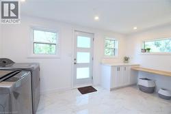 Bright utility room featuring white cabinetry, a light wood-finish folding counter, and recessed lighting - 