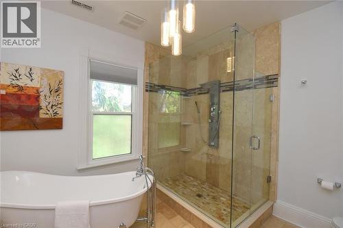 Glass-enclosed shower featuring a shower panel system, stone tile surround, and mosaic tile accent band - 89 Lynden Road, Lynden, ON 