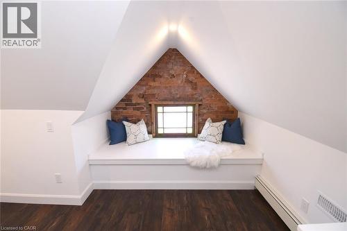 Built-in window seat with exposed brick accent wall, stained glass wood-frame window, and recessed lighting - 89 Lynden Road, Lynden, ON 