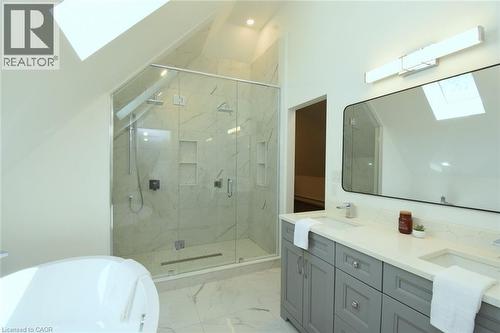 Spacious bathroom featuring a dual vanity with light gray cabinetry, a large walk-in shower with glass enclosure and built-in niches, and a freestanding soaking tub - 89 Lynden Road, Lynden, ON 