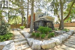 Backyard featuring a stone paver pathway, large boulder retaining wall, and mature trees - 
