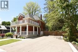 Red brick exterior featuring a full-width covered porch with white columns and railings. Also showing private double wide driveway - 