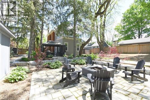 Expansive backyard featuring a paver patio with a built-in fire pit, stone retaining walls, mature trees, and a screened gazebo - 89 Lynden Road, Lynden, ON 