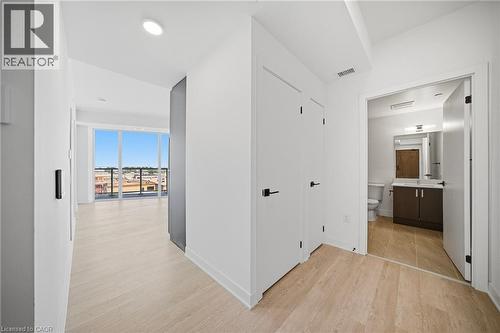 Hallway with light wood-finish flooring, white walls, and contemporary black hardware on doors - 2782 Barton Street E Unit# 516, Hamilton, ON - Indoor Photo Showing Other Room
