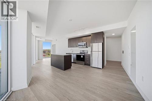 Open concept kitchen featuring dark wood cabinetry, stainless steel appliances, and a central island with a solid surface countertop - 2782 Barton Street E Unit# 516, Hamilton, ON - Indoor Photo Showing Kitchen