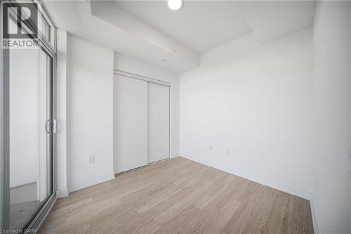 Room featuring light wood-finish flooring, white walls, and a sliding glass door providing exterior access - 2782 Barton Street E Unit# 516, Hamilton, ON - Indoor Photo Showing Other Room