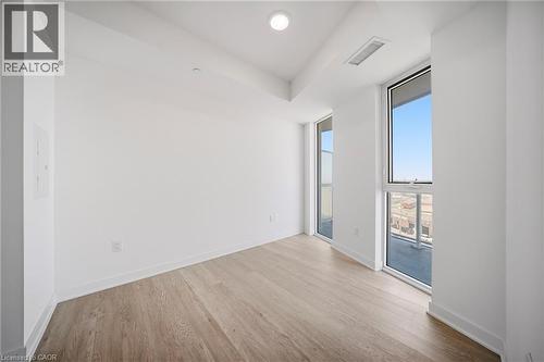 Light wood-finish flooring complements crisp white walls in this room featuring two floor-to-ceiling windows, recessed ceiling lighting, and clean baseboards - 2782 Barton Street E Unit# 516, Hamilton, ON - Indoor Photo Showing Other Room