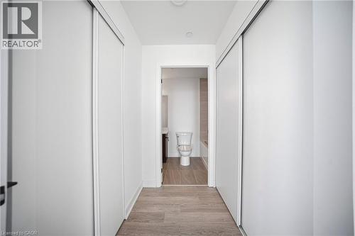 Hallway featuring light wood-finish flooring, white walls, and two sets of sliding closet doors - 2782 Barton Street E Unit# 516, Hamilton, ON - Indoor Photo Showing Other Room