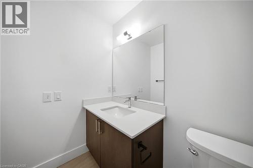 Bathroom featuring a wood-finish vanity with dual doors, a white integrated sink, and a light-colored countertop - 2782 Barton Street E Unit# 516, Hamilton, ON - Indoor Photo Showing Bathroom