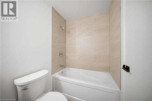 Bathroom featuring a white tub and shower combination with beige tiled walls - 2782 Barton Street E Unit# 516, Hamilton, ON - Indoor Photo Showing Bathroom