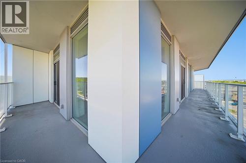 Expansive exterior balcony with a grey finished floor, clear glass railings, and multiple large windows - 2782 Barton Street E Unit# 516, Hamilton, ON - Outdoor With Balcony With Exterior