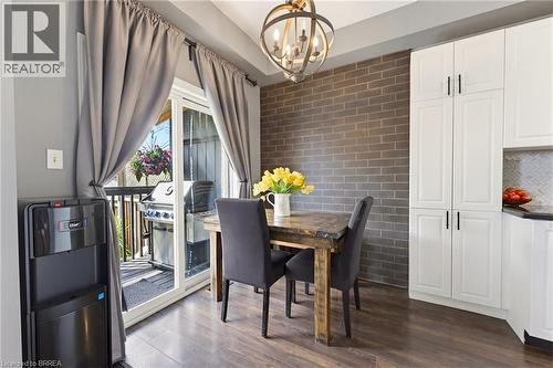 Dining area with wood-finish flooring featuring a brick-accented wall and a direct-access sliding glass door to an outdoor deck - 100 Chester Drive Unit# 16, Cambridge, ON - Indoor Photo Showing Dining Room