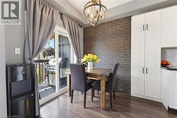 Dining area with wood-finish flooring featuring a brick-accented wall and a direct-access sliding glass door to an outdoor deck - 