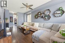 Living area featuring wood-finish flooring, a ceiling fan with integrated lighting, and a window with blinds - 