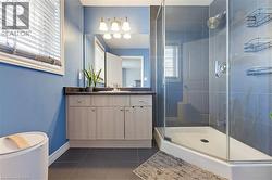 Bathroom featuring a framed glass shower enclosure, blue wall paint, and dark tile flooring - 