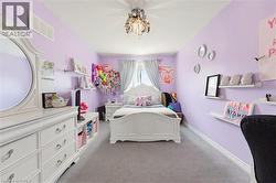 Carpeted room with lavender walls, a decorative ceiling light fixture, and white baseboards - 
