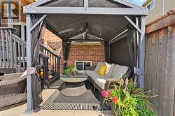 Outdoor patio area with a covered gazebo structure, brick exterior, and a wooden privacy fence - 