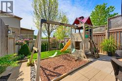 Fenced backyard featuring a wood playset with swings and slide, a mulched play area, and a paver patio - 