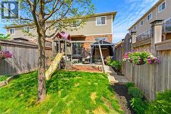 Fenced backyard featuring a manicured lawn, an established tree, a children's play structure, and a patio area with a gazebo - 