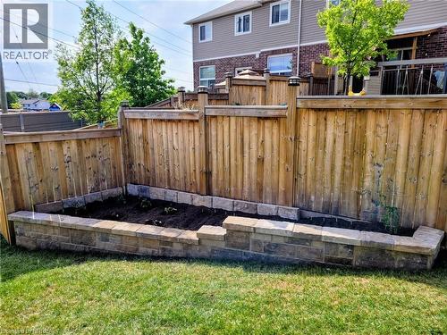 Manicured lawn with a stone-bordered raised garden bed - 100 Chester Drive Unit# 16, Cambridge, ON - Outdoor With Exterior
