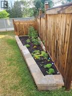 Wood-paneled fencing enclosing a landscaped planting bed with stone block retaining walls, featuring integrated post-top lighting - 