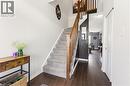Welcoming entryway featuring dark wood-finish flooring, a carpeted staircase with wood railings, white baseboards, and a white interior door - 100 Chester Drive Unit# 16, Cambridge, ON  - Indoor Photo Showing Other Room 