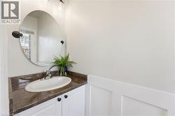 Bathroom vanity featuring a white oval undermount sink, dark countertop, and white cabinetry with black hardware - 