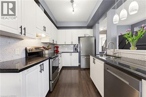 Modern kitchen featuring white cabinetry, dark countertops, and stainless steel appliances - 100 Chester Drive Unit# 16, Cambridge, ON - Indoor Photo Showing Kitchen With Double Sink With Upgraded Kitchen