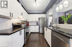 Modern kitchen featuring white cabinetry, dark countertops, and stainless steel appliances - 