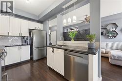 Modern kitchen featuring white cabinetry, dark countertops, and stainless steel appliances - 