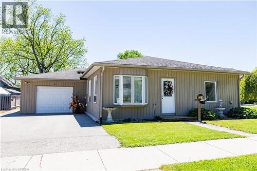 Single-story residence featuring light brown vertical siding and a dark shingle roof - 100 Mechanic Street W, Waterford, ON - Outdoor