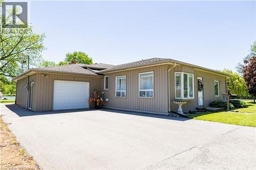 Ranch-style exterior featuring a single-car garage, bay window, and a spacious paved driveway - 100 Mechanic Street W, Waterford, ON - Outdoor