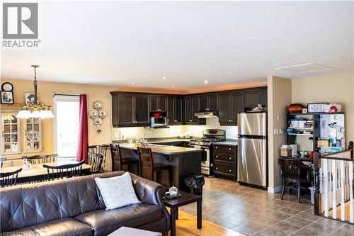 Kitchen and dining area featuring dark wood cabinetry, stainless steel appliances, and an island with bar seating - 100 Mechanic Street W, Waterford, ON - Indoor Photo Showing Kitchen With Stainless Steel Kitchen