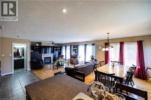 Open-concept living area featuring wood-finish flooring, a contemporary fireplace with a white mantel, and recessed ceiling lighting - 100 Mechanic Street W, Waterford, ON - Indoor Photo Showing Other Room With Fireplace