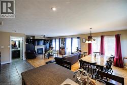 Open-concept living area featuring wood-finish flooring, a contemporary fireplace with a white mantel, and recessed ceiling lighting - 