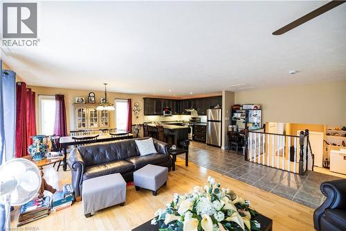 Open-concept living area featuring wood-finish flooring, a dining space with chandelier lighting, a kitchen with dark cabinetry and stainless steel appliances, and a tiled entryway - 100 Mechanic Street W, Waterford, ON - Indoor Photo Showing Living Room