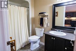 Bathroom featuring a shower/tub combination, floor-set toilet, and a vanity with a dark countertop and under-sink storage - 