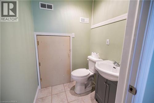 Bathroom featuring light green walls, white crown molding, a white toilet, a white porcelain sink, and a gray vanity cabinet - 100 Mechanic Street W, Waterford, ON - Indoor Photo Showing Bathroom
