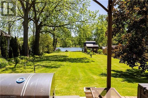 Expansive grassy lawn extending towards a body of water, bordered by mature trees and lush foliage - 100 Mechanic Street W, Waterford, ON - Outdoor