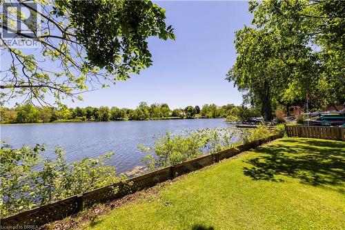 Expansive waterfront property featuring a manicured lawn, established perimeter fencing, and mature trees - 100 Mechanic Street W, Waterford, ON - Outdoor With Body Of Water With View