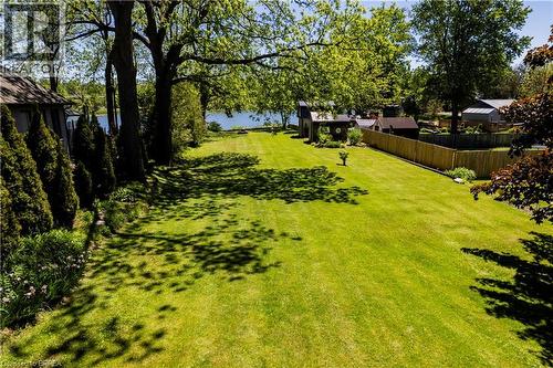 Expansive green lawn with mature trees and a partial water feature visible in the background - 100 Mechanic Street W, Waterford, ON - Outdoor